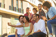 © Mangostar - Cheerful happy interracial friends taking group selfie outside. Multiethnic men and women posing and laughing at phone camera. Friendship concept