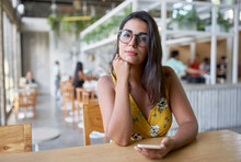 Lifestyle portait of confident beautiful natural brunette millennial businesswoman sitting in modern restaurant waiting for friends