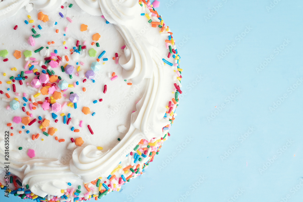 Top view of a cake with colorful sprinkles on a light blue background ...