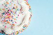 Top view of a cake with colorful sprinkles on a light blue background