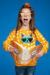 Portrait of a cheerful 8-year-old girl in a bright sweater with a cat drawing, in glasses and with a photo album in her hands