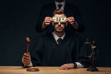 Cropped View Of Man Standing And Covering Face Of Judge With Bribe On Black