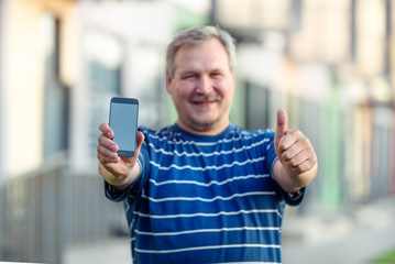 Close-up of happy man hand showing blank screen of smartphone on street