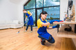 © xartproduction - professional cleaning service. Two women in working uniform, in aprons, divide the cleaning of the kitchen of a private house, cottage. Washing floor