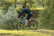 © Mountains Hunter - Cyclist in shorts and jersey on a modern carbon hardtail bike with an air suspension fork rides off-road on the orange-red hills at sunset evening in summer