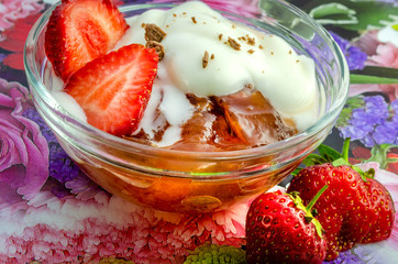 A yummy treat of a bowl of jelly and cream with chocolate tops and strawberries. 