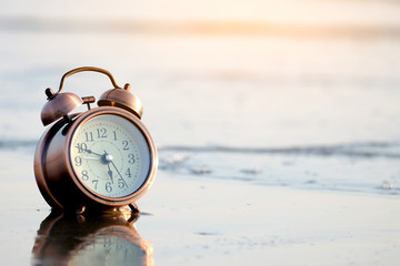 Morning of a new day, alarm clock on the beach sunlight in morning. Health and holiday concept.