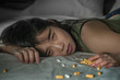 young beautiful desperate and wasted addict Asian Japanese woman taking drug overdose lying on bed feeling sick and depressed suffering depression breakdown