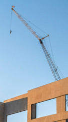 Vertical Building under construction with metal crane and blue sky background