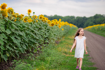 Pretty girl walking on the road along the field sunflower.