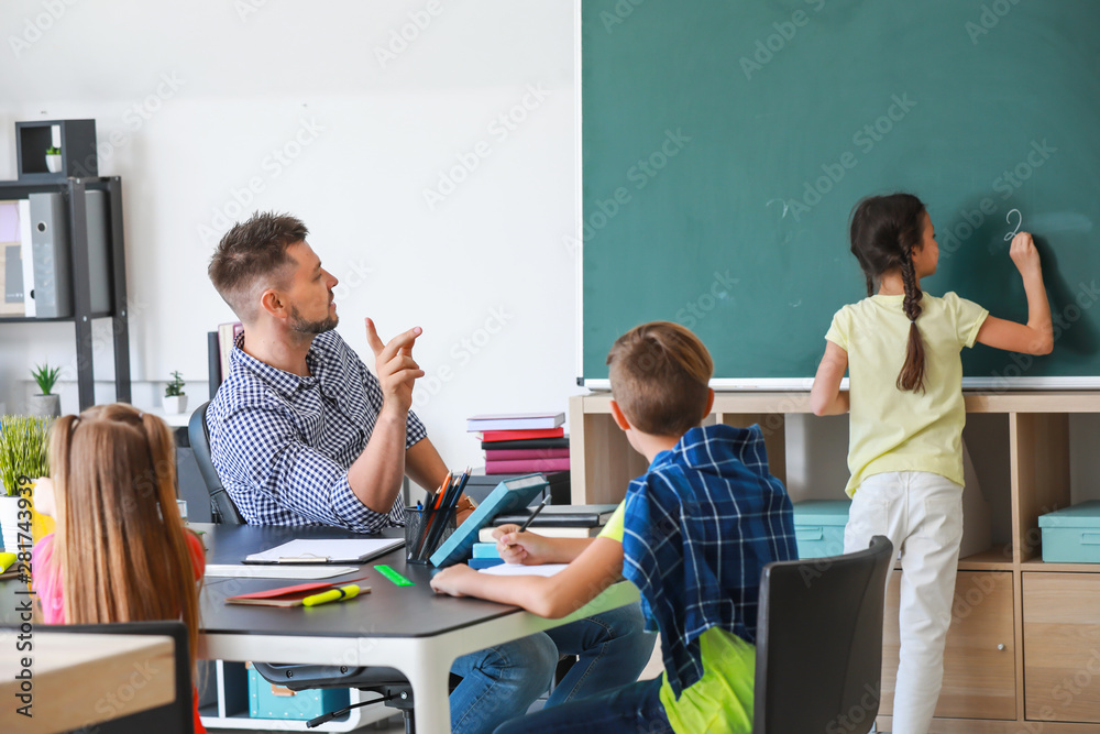 Cute children with teacher during lesson in classroom