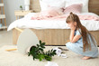 Little girl in room with dropped houseplant and paper pieces on carpet