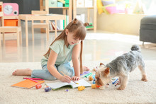 Cute Little Girl With Dog Painting While Sitting On Carpet