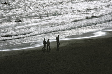 pedestrian on the beach with sparkling reflection of sunlight on the sea surface