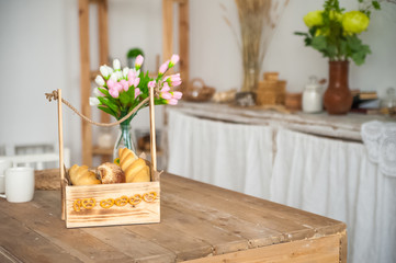 Wall Mural - Bread in a textured wooden box in the kitchen in a rustic style. Breakfast, bread, white cups in the interior of bright Scandinavian cuisine.