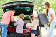 Familie mit Kindern packen Koffer in das Auto
