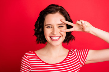 Wall Mural - Photo of cute rejoicing woman imagining as if her fingers were scissors while isolated with red background