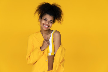 Happy young african american woman wear stylish yellow clothes looking at camera, smiling positive black teenager fashion girl isolated on summer wall studio background, portrait, copy space