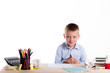 © tavrox - Cute little school boy with huge smile sitting at his desk on white background. Happy intelligent children in shirt