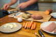 Vorbereitungen in der Küche für das Abendessen, Möhren und Butter im Vordergrund, ein Mann, Knoblauch und Süsskartoffel unscharf im Hintergrund, Nahaufnahme