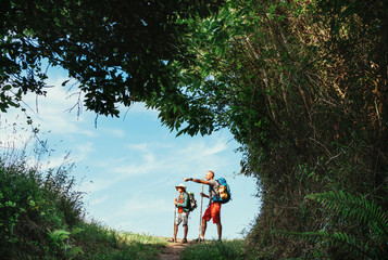 Wall Mural - father and son backpackers hiking by the forest pathway, taking a short rest break. happy parents tr