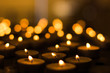 atmospheric religion twilight interior table with small candles fire illumination and unfocused yellow bokeh background