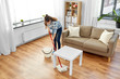 © Syda Productions - people, housework and housekeeping concept - happy asian woman or housewife with mop cleaning floor under table at home
