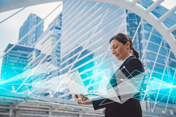 Poster - Happy young businesswoman working on laptop computer in the city.Modern city with network connection concept.global network,data exchanges,communication,smart city.