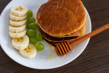 Wall Mural - pancakes on a plate with honey, grapes and banana slices for breakfast