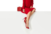 Beautiful Legs Woman Wearing Red Dress And High Heels Shoes Sitting On White Bench. Copyspace.