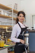 © nikodash - Beautiful women barista smiling and using coffee machine in coffee shop