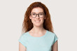 Millennial ginger woman wearing glasses looking at camera pose indoors