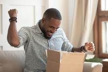 Excited African Man Customer Receive Open Parcel Box At Home