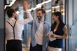 Friendly male colleagues giving high five talking in office hall