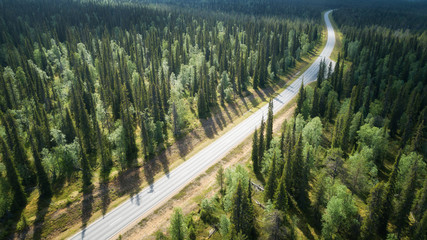 Wall Mural - Aerial view from above of country road through the green summer forest in Lapland. Beautiful fir trees. Drone photography.