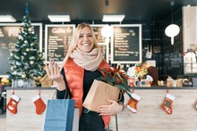 Happy Smiling Blonde In Coffee Shop With Shopping Bags And Red Poinsettia Christmas Flower