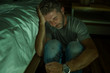 © TheVisualsYouNeed - dramatic home portrait of young desperate and depressed lonely man sitting on bedroom floor crying sick suffering anxiety crisis and depression problem feeling helpless