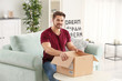© Africa Studio - Young man unpacking parcel at home