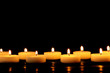 Burning candles on table against black background, space for text