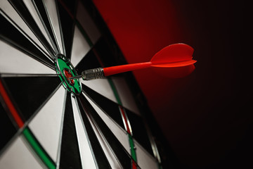 Color arrow hitting target on dart board against red background