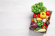 Crate with different fresh vegetables on light background, top view. Space for text