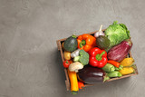 Fototapeta Kuchnia - Crate with different fresh vegetables on grey background, top view. Space for text