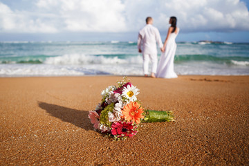 Wall Mural - Just married. Selective focus on beautiful flowers bouquet in front of the wedding couple with beach background