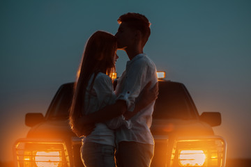 silhouettes of two young people in the light of burning car headlights in the background. the guy hu