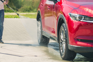 Wall Mural - Manual car wash with pressurized water in car wash outside. Summer Car Washing. Cleaning Car Using High Pressure Water. Washing  with soap. Close up concept.