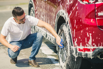 Wall Mural - Car detailing - the man holds the microfiber in hand and polishes the car. Selective focus. Car detailing series : Worker cleaning red car. 