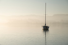 Stunning Unplugged Fine Art Landscape Image Of Sailing Yacht Sitting Still In Calm Lake Water In Lake District During Peaceful Misty Autumn Fall Sunrise