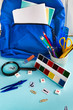 © Yana Kovalenko - Set of school supplies from a school backpack with notebooks, pens, pencils, paint numbers on a blue background. Back to school