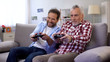 © motortion - Senior male with son playing video game using joystick, having fun together