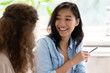 © fizkes - Asian woman talking with colleague sitting at desk indoors